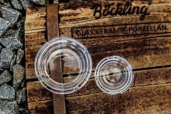 Zwei klare Glasuntersetzer auf einer rustikalen Holzkiste mit Aufschrift 'Böckling'.