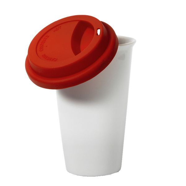 Eine einzelne, leere, weiße Keramiktasse mit einem roten Silikondeckel, der schräg aufliegt, vor einem weißen Hintergrund.